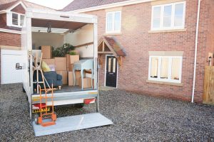 Removal Truck Waiting To Be Unloaded Outside New Home On Moving Day